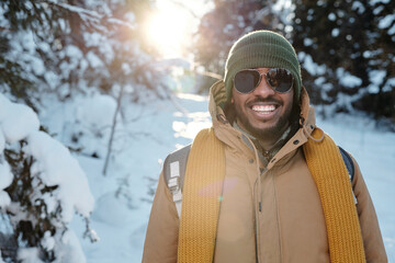 Happy young African man in sunglasses and warm winterwear enjoying chill