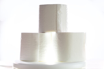 Three rolls of toilet paper so requested in the pandemic, front photo with a light in the center. White background.