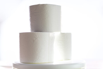 Three rolls of toilet paper so sought after in the pandemic, pictured diagonally with a light in the center.