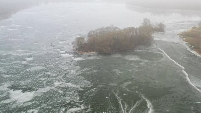 top view of an island in the middle of a frozen lake and fishermen catching fish