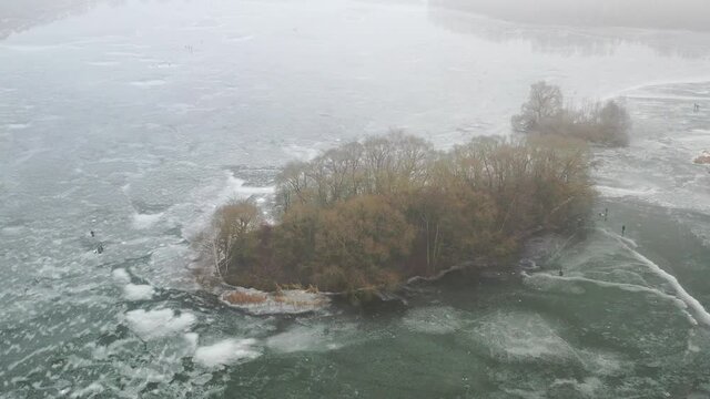 top view of an island in the middle of a frozen lake and fishermen catching fish
