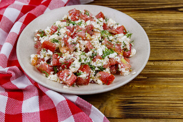 Tasty salad of tomato, cottage cheese, dill and olive oil on wooden table