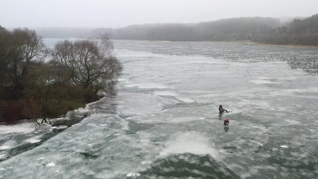 top view of an island in the middle of a frozen lake and fishermen catching fish