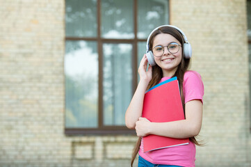 Fototapeta premium Listen for education you want. Happy child wear headphones outdoors. Listen technologies. Listening comprehension. English school. Modern lifestyle. Audio courses. Language is future, copy space