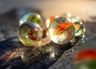 Poster A group of marbles on the sidewalk near a marble pot illuminated by golden sun rays. © mslok