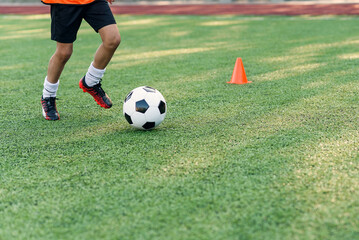 Soccer player kicking ball on field. Soccer players on training session. Close up footballer feet kicking ball on grass.