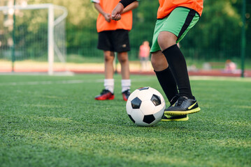Soccer player kicking ball on field. Soccer players on training session. Close up footballer feet kicking ball on grass.