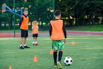 Naklejka premium Soccer player kicking ball on field. Soccer players on training session. Teen footballer kicking ball on green grass.