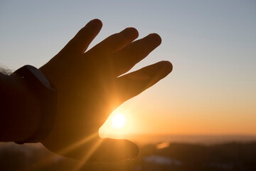 man's hand reaches out to the setting sun, the concept of hope, desire, dreams.. Conceptual design.