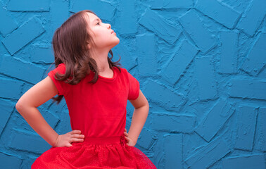 a little girl in a red dress sits against the wall and she is arrogant