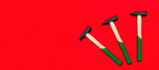 Three hammers isolated on a red background with place for text. Shop banner with construction tools. New Year or Christmas festive backdrop. One of the basic home use instrument for hammering nails