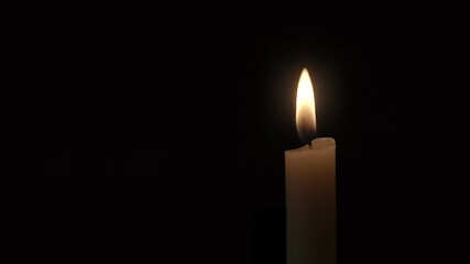 Candle. Close-up of a single candle flame burning against a black background. - Powered by Adobe