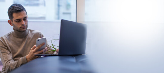 man working at home with laptop and mobile phone