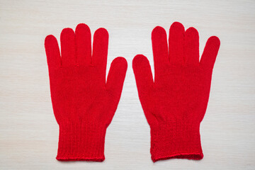 Red work gloves on a wooden light background. Top view of knitted work gloves for the garden, vegetable garden, dirty work