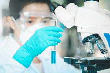 Doctor or scientist in laboratory holding liquid vaccines in medical research lab or science...