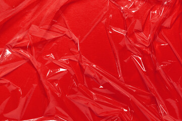 Wrinkled cling film, red vinyl art background, plastic texture.