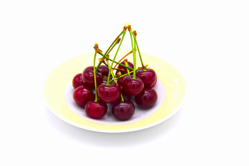 A handful of cherries with the branches lying on the saucer