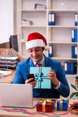 Young male employee celebrating Christmas at workplace