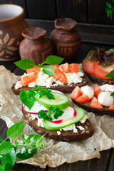 Variety of toast sandwiches with eggs, raddish, tomatoes, cucumber, avocado and sweet pepper