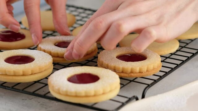 Female hands put cookies on the second cookie with jam. Female hands a making homemade biscuit shortbread cookies with jam. Kurabye cookies with raspberry jam. Christmas cookies with jam.