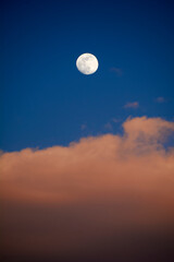 Moon in blue sky with white clouds