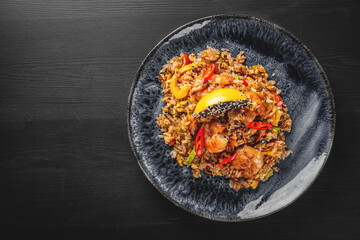 Fried rice with shrimp and vegetables in plate on wooden table background