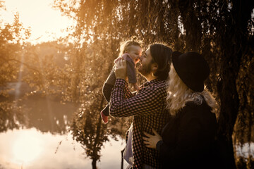 Happy young family concept. Young father and mother play with their 6 month old baby child girl in the park.