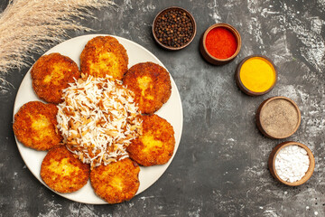 top view fried cutlets with cooked rice and seasonings on a dark floor food meat dish