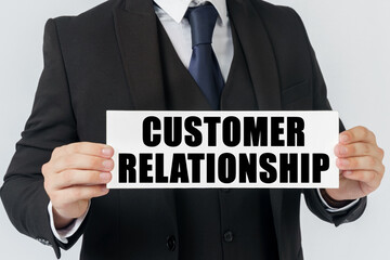 Obraz premium A businessman holds a sign in his hands which says - CUSTOMER RELATIONSHIP