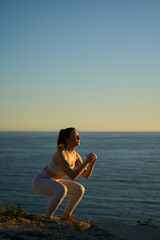 young spanish girl doing exercise in front of the mediterranean sea at sunset