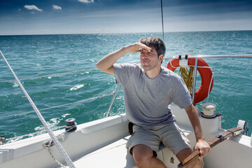 Young man on sailboat looking for direction while sailing