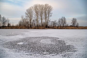 Frosty evening on the lake, transparent ice with snowflakes in the form of stars, sunset sky.