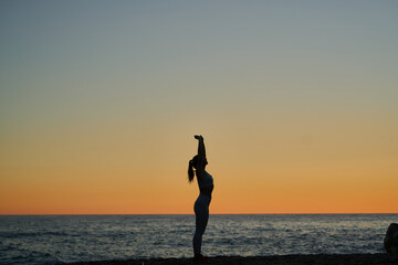 young spanish girl doing exercise in front of the mediterranean sea at sunset