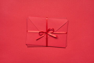 Top above flatlay close up view photo of pile stack of envelopes tied with silky ribbon isolated vivid color red background