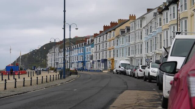 Row of brightly coloured houses on Welsh seaside resort Aberystwyth promenade on overcast day.