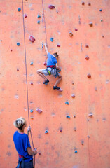 A boy climbs the wall, a coach teaches a child