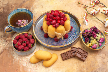 Side view of hot herbal tea soft cake with fruits chocolate bars on mixed color table