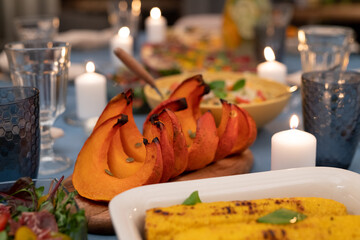 Part of festive table with salad, grilled corn, baked pumpkin and other food