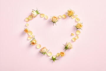 Heart made of roses on pink background. Floral flat lay style composition, top view. Valentines Day, Mothers Day, birthday greeting card.