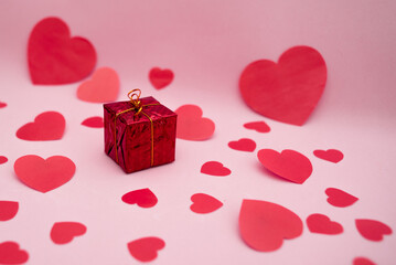 Red gift box and red hearts on a pink background. Valentine's day gift.