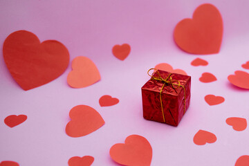 Red gift box and red hearts on a pink background. Valentine's day gift.