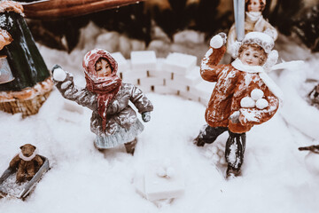 Toy figurines of people in the snow. Christmas decorations in a shop window