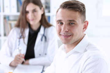 Fototapeta premium Satisfied happy handsome smiling male patient with doctor at her office. High level and quality medical service, therapeutist consultation, work and career, physical, healthy lifestyle concept