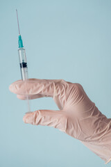 Close-up of a hand in white medical glove holding a medical syringe