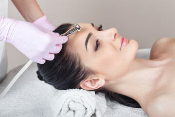 Naklejka premium The cosmetologist makes the procedure Microdermabrasion of the face skin of a beautiful girl in a beauty salon.Cosmetology and professional skin care.