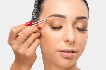 Makeup artist combs  and plucks eyebrows after dyeing in a beauty salon.Professional makeup and...