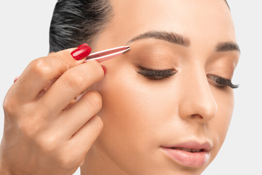 Makeup artist combs  and plucks eyebrows after dyeing in a beauty salon.Professional makeup and cosmetology skin care.