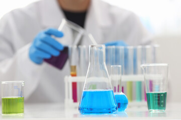A male chemist holds test tube of glass in his hand overflows a liquid solution of potassium permanganate conducts an analysis reaction takes various versions of reagents using chemical manufacturing