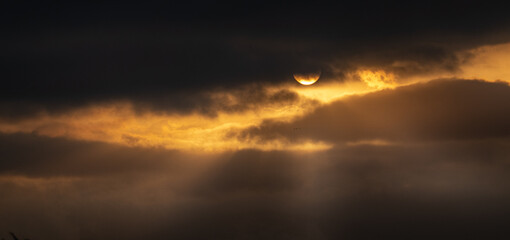 Sun behind clouds at dusk