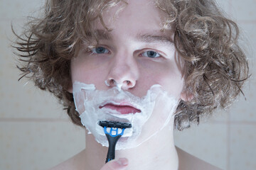 A man shaves with a machine in the bathroom.